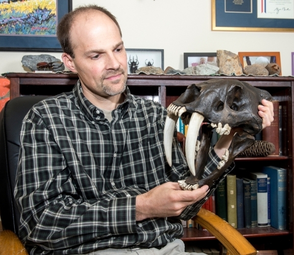 Photo of Doug Emlen holding a sabertooth skull