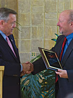 Ron Tschetter, director of the Peace Corps, presents a plaque to UM.