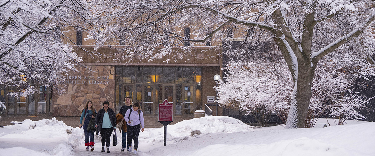 Students walk in front of UM's library in the snow