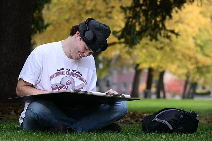 A student studying on the UM Oval. 