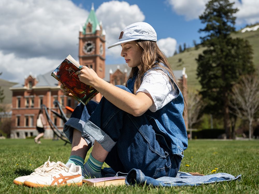 A student sits and reads on the UM Campus
