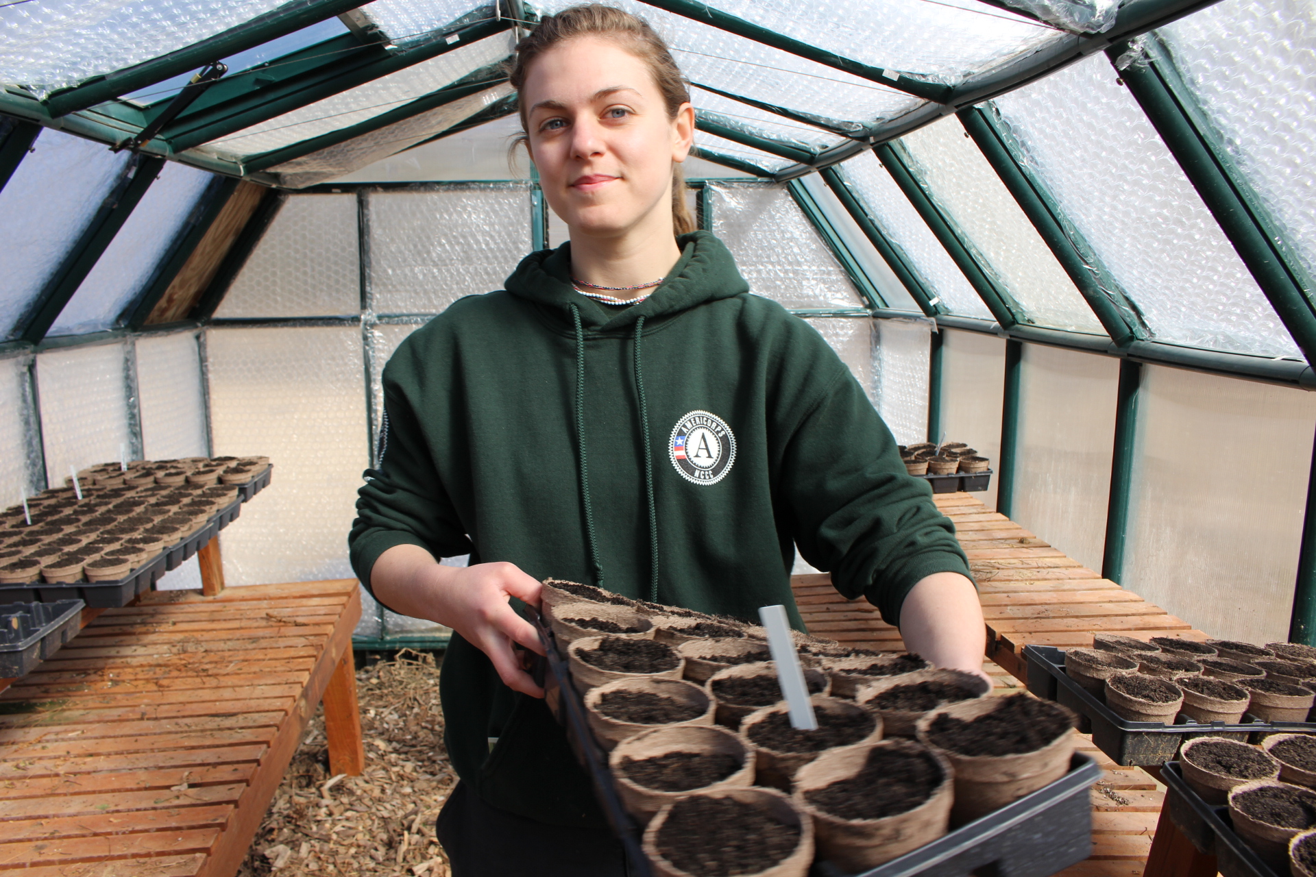 An NCCC member works with plants in a greenhouse
