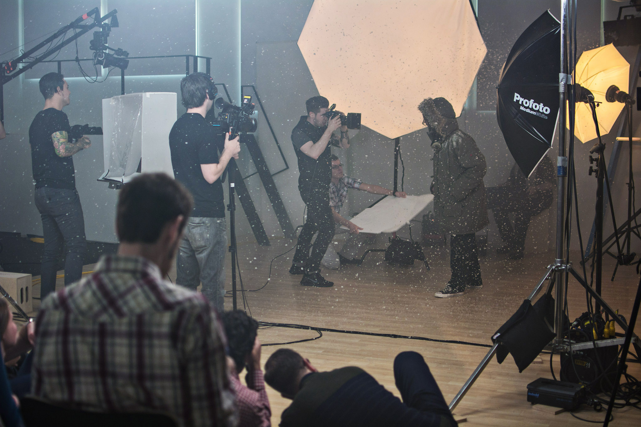 group of students on set with camera and lights filming an actor in fake snow