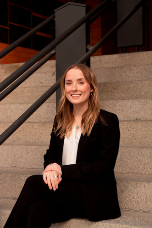 ASUM President Chase O'Brien sitting on steps in a suit. 