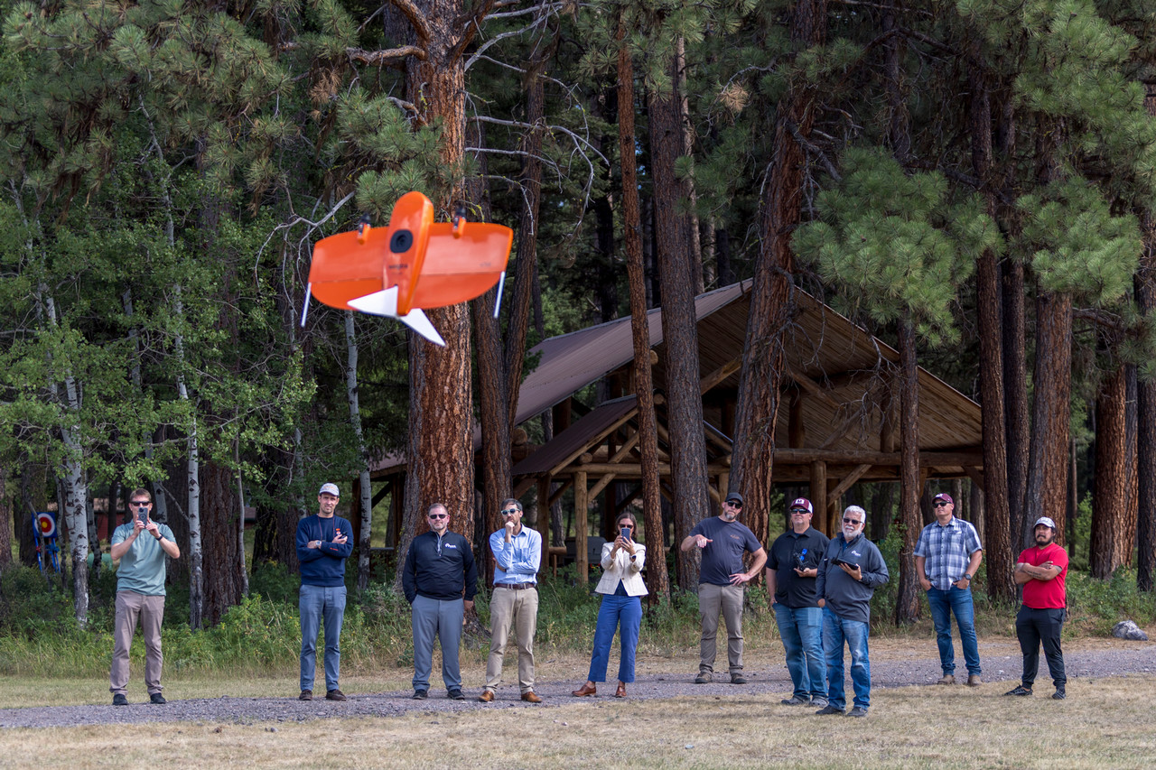 Group of people look on as a drone lands at Lubrecht Experimental Forest