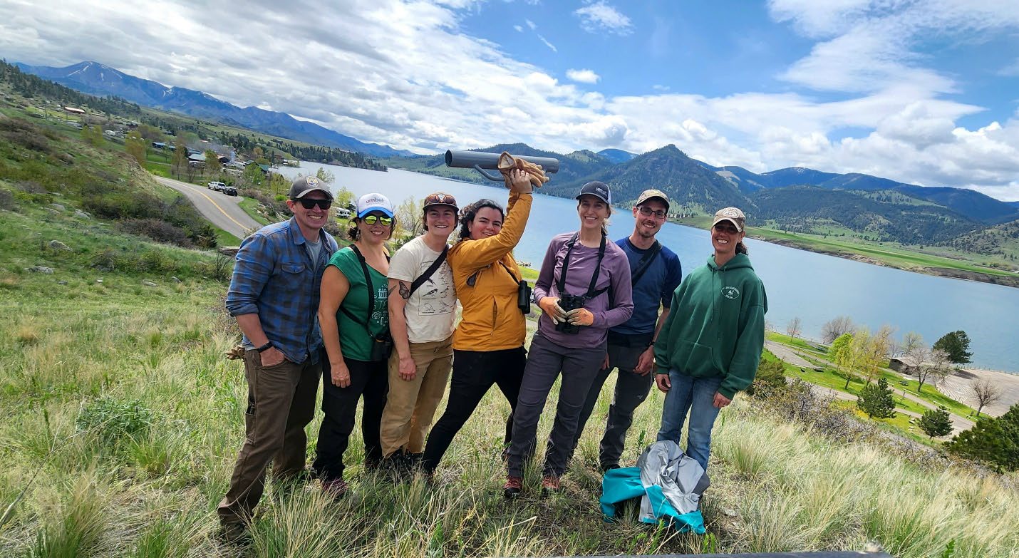 Field Crew gathered on hill with lake in background. 