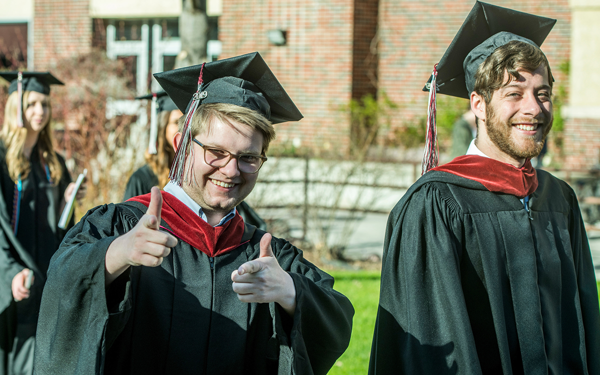 Two students smile as they walk toward their graduation ceremony