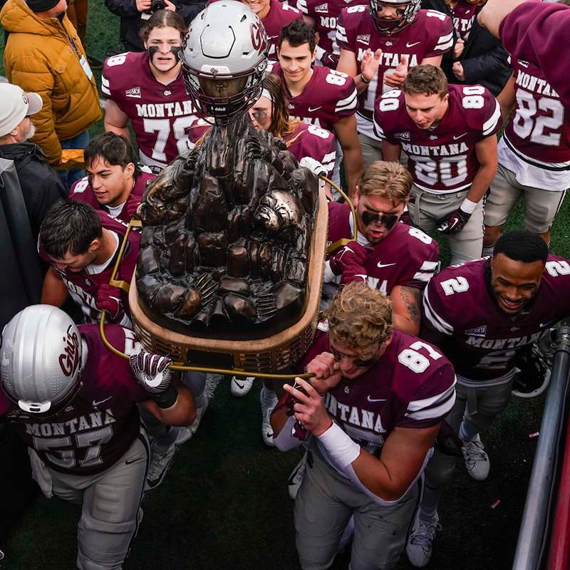 Griz football players carry the Great Divide Trophy