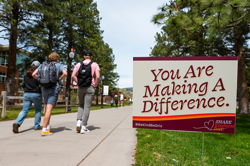 Three students walk past a sign that reads "You are making a difference"