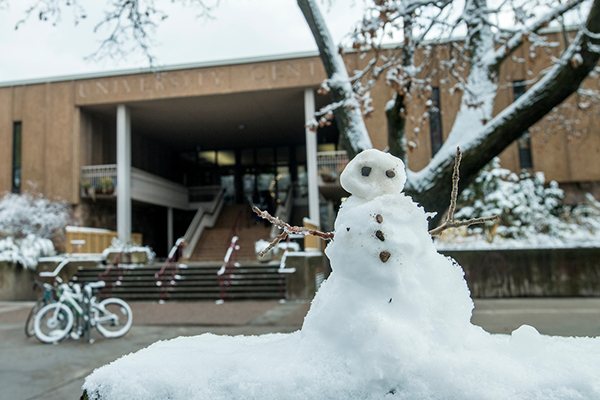 A mini snowman sits on a bench outside the University Center.