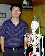 Dr. Dongya Yang standing next to a life-size human skeleton model in an indoor room.