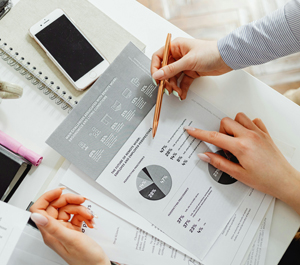 Co-workers look over a pie chart on a printed piece of paper.