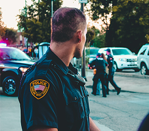 A police office looks as two officers detain a suspect.
