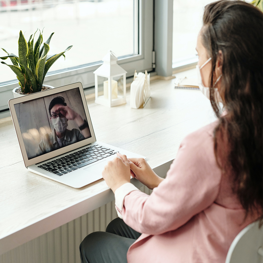 woman sitting at desk in front of laptop in a video call
