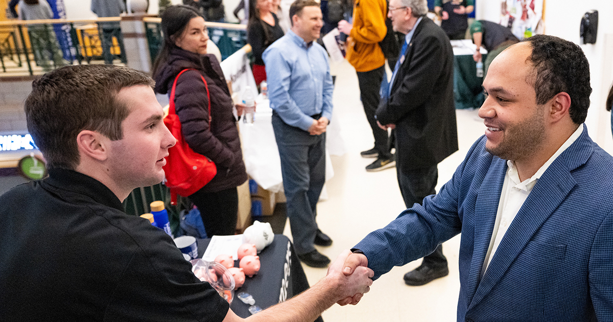 UM College of Business student shakes hands with an employer at a career fair.