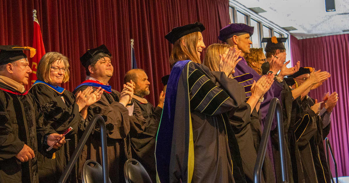 UM College of Business faculty members applaud graduates at the Master’s Hooding Ceremony.