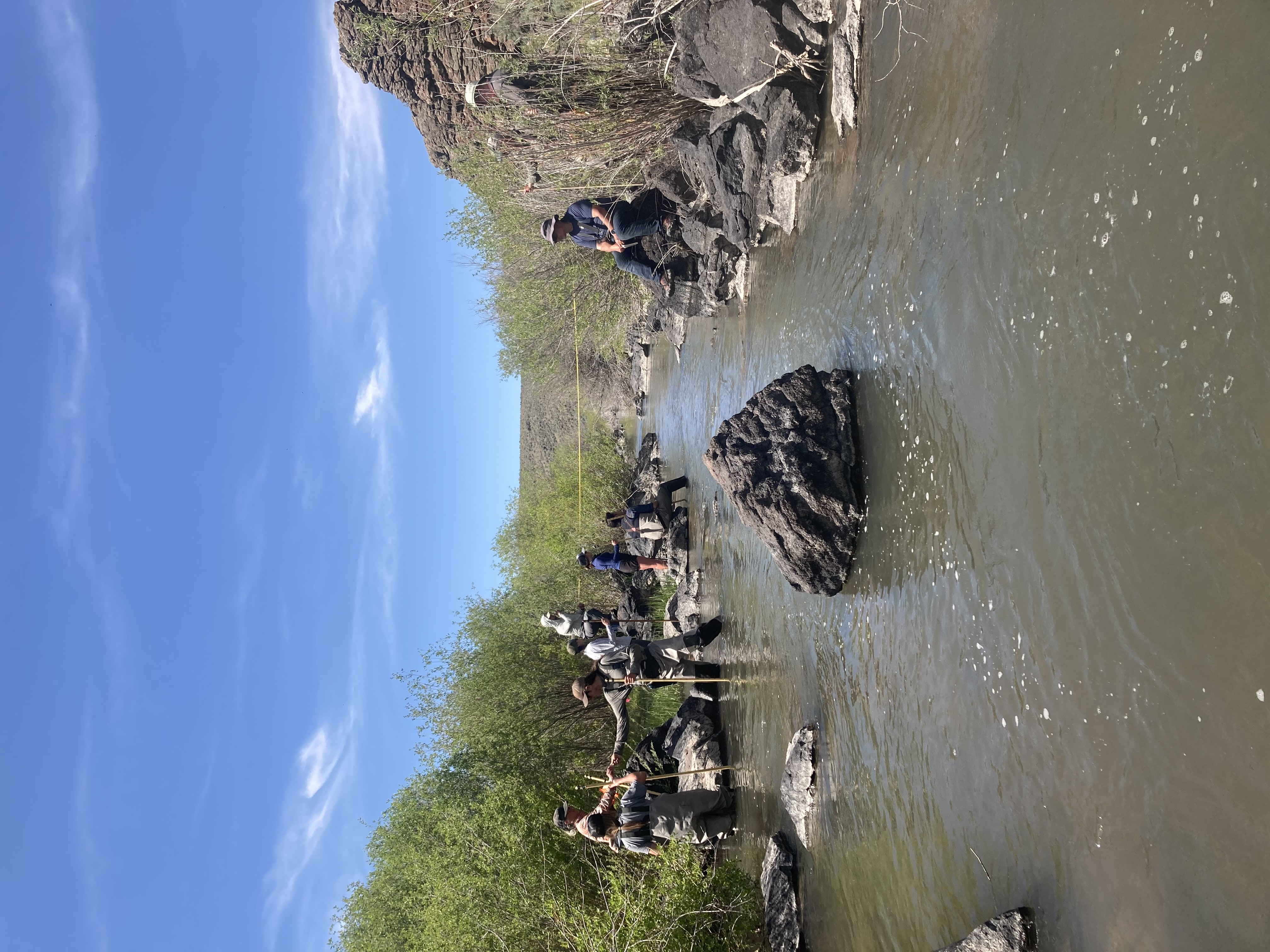A group of researchers collect data and water in a rocky stream.