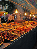 cooking sheets full of food at an evening market
