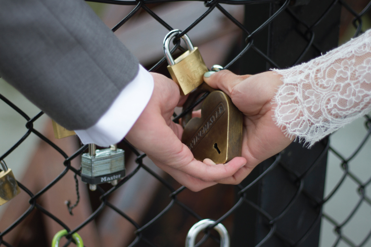 Couple closing a heart-shaped lock together on the footbridge