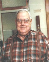 Portrait of Dick Juday wearing glasses and a red plaid shirt indoors.