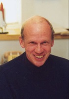 Smiling Thomas B. Brill in a dark sweater, shown in a close-up portrait indoors.