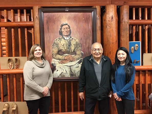 Susan Penfield, Richard Littlebear, and Mizuki Miyashita standing in front of a painting of a native american
