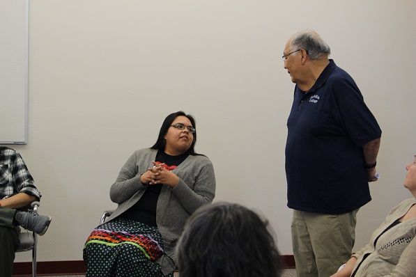 richard littlebear talking to someone sitting in a circle
