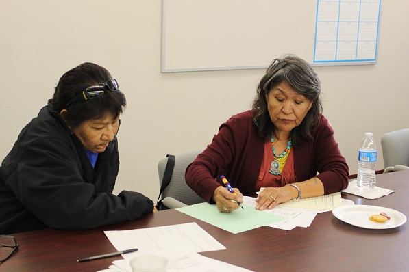 two people working together with one writing on some paper and the other watching