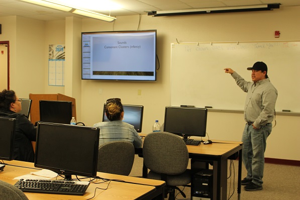 mike turcotte pointing at a projection screen standing a teaching at the front of the classroom