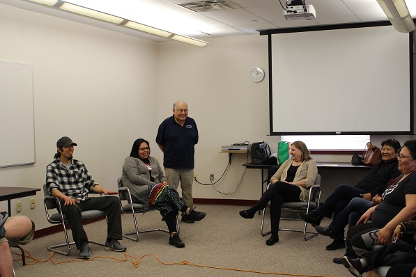richard littlebear standing in a circle of seated people