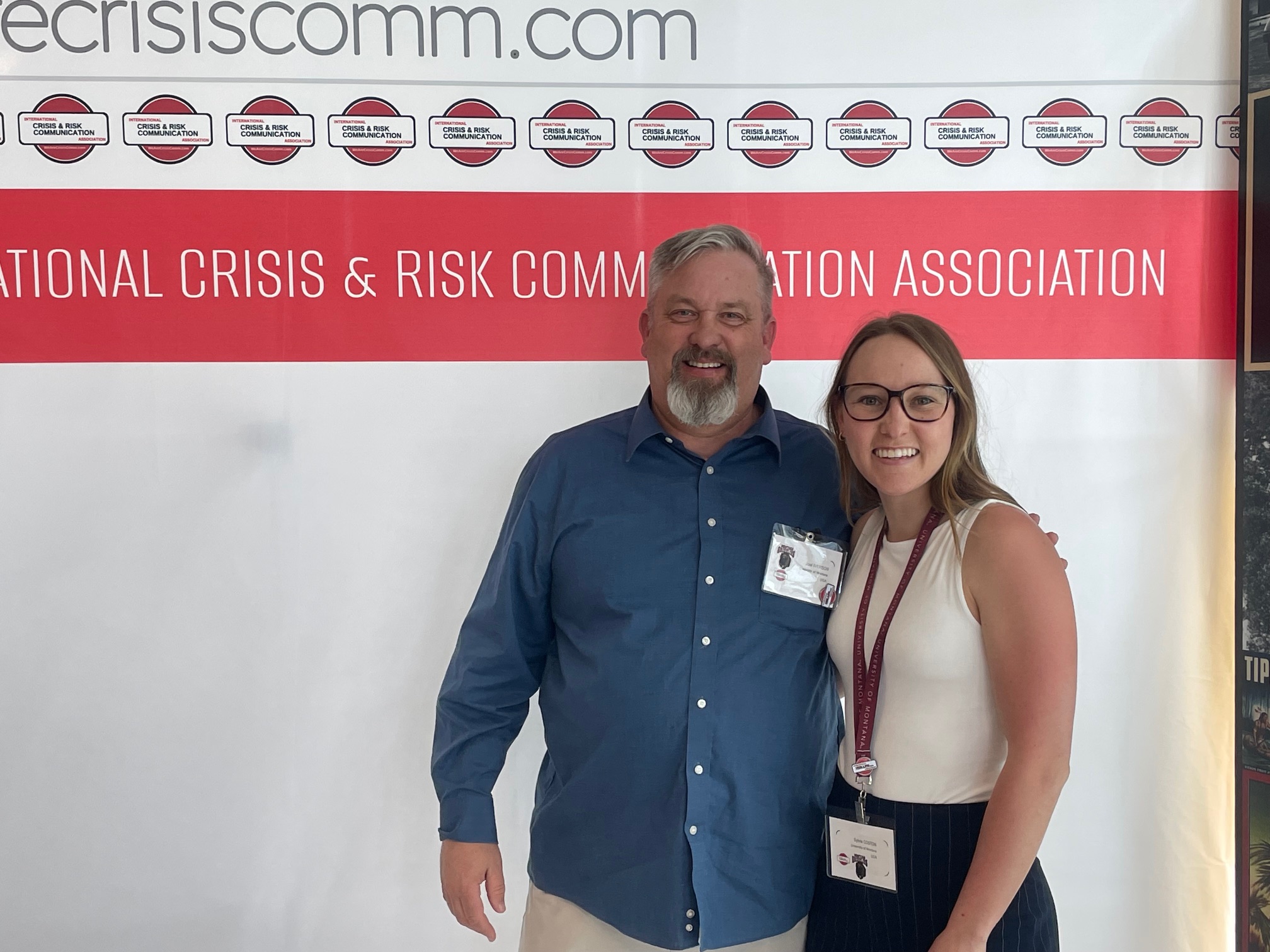 A COMX Professor and a graduate student pose at a national academic conference. Both are smiling. 