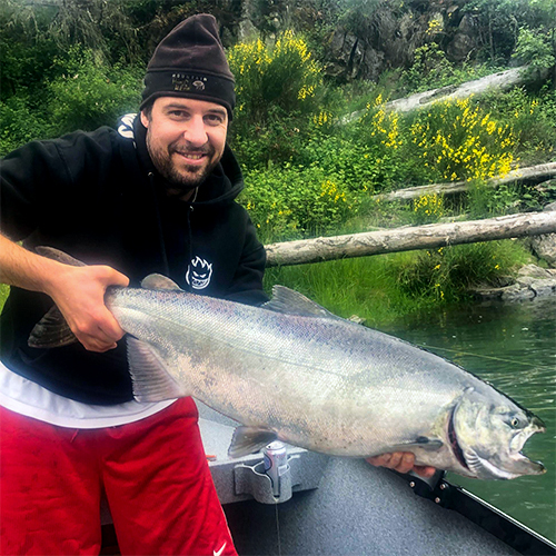 Mike Miller holding a large fish in both hands while standing in a boat