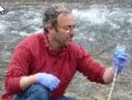 shot of Mike Schwartz using a scientific instrument next to a river