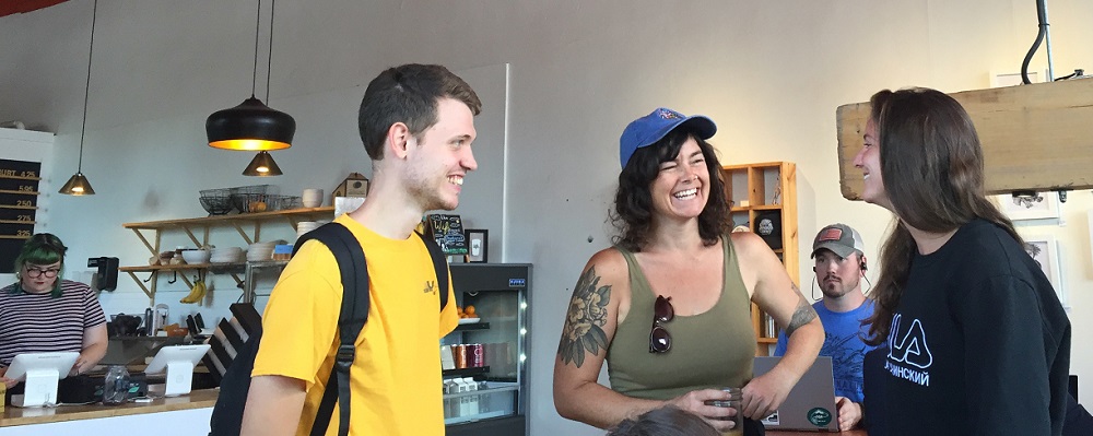 MFA students Will Fesperman, Kelly Schirmann, and Rebecca Swanberg smile in a cafe.