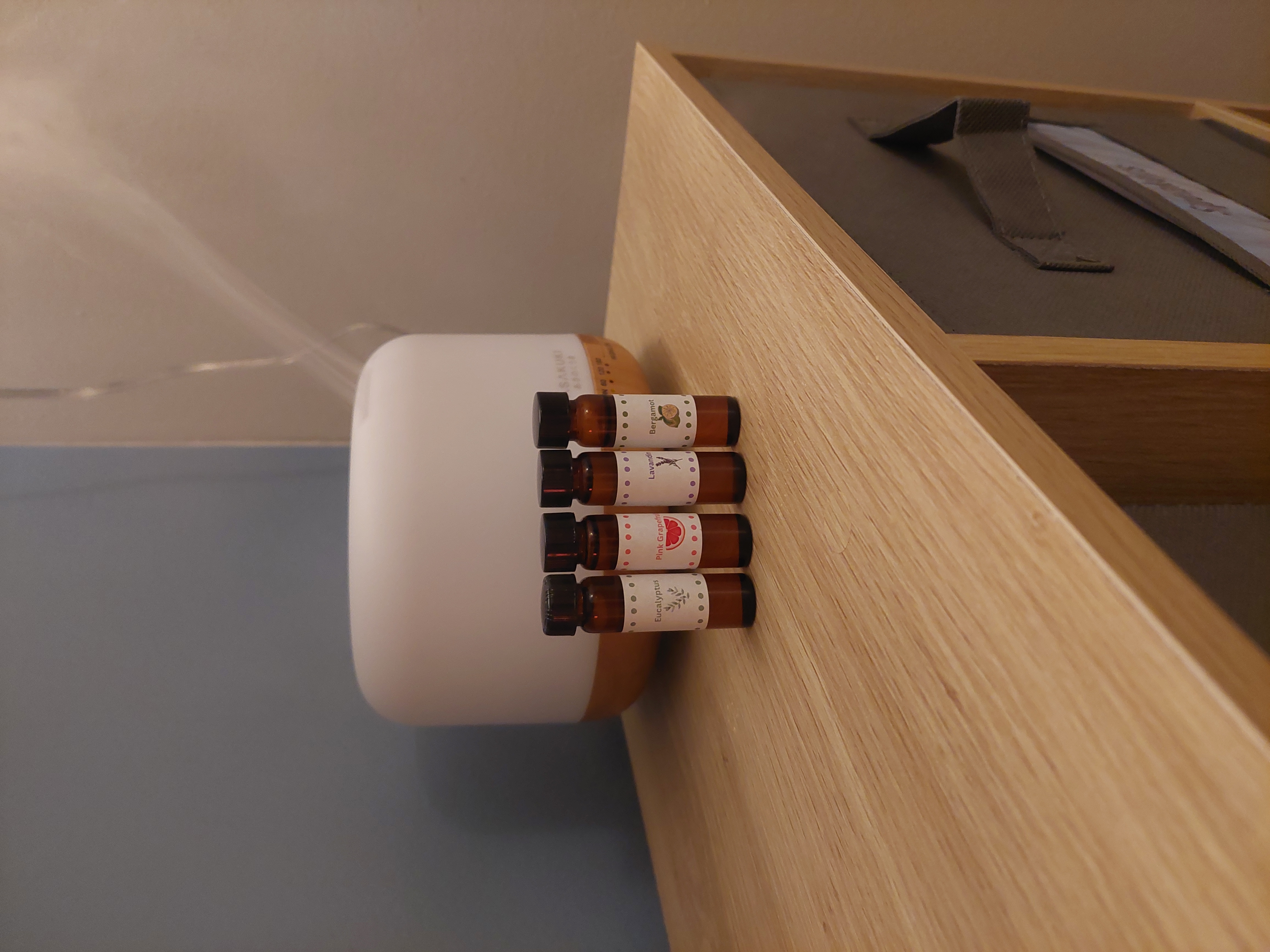 a row of essential oil bottles in front of a diffusers on top of a shelf
