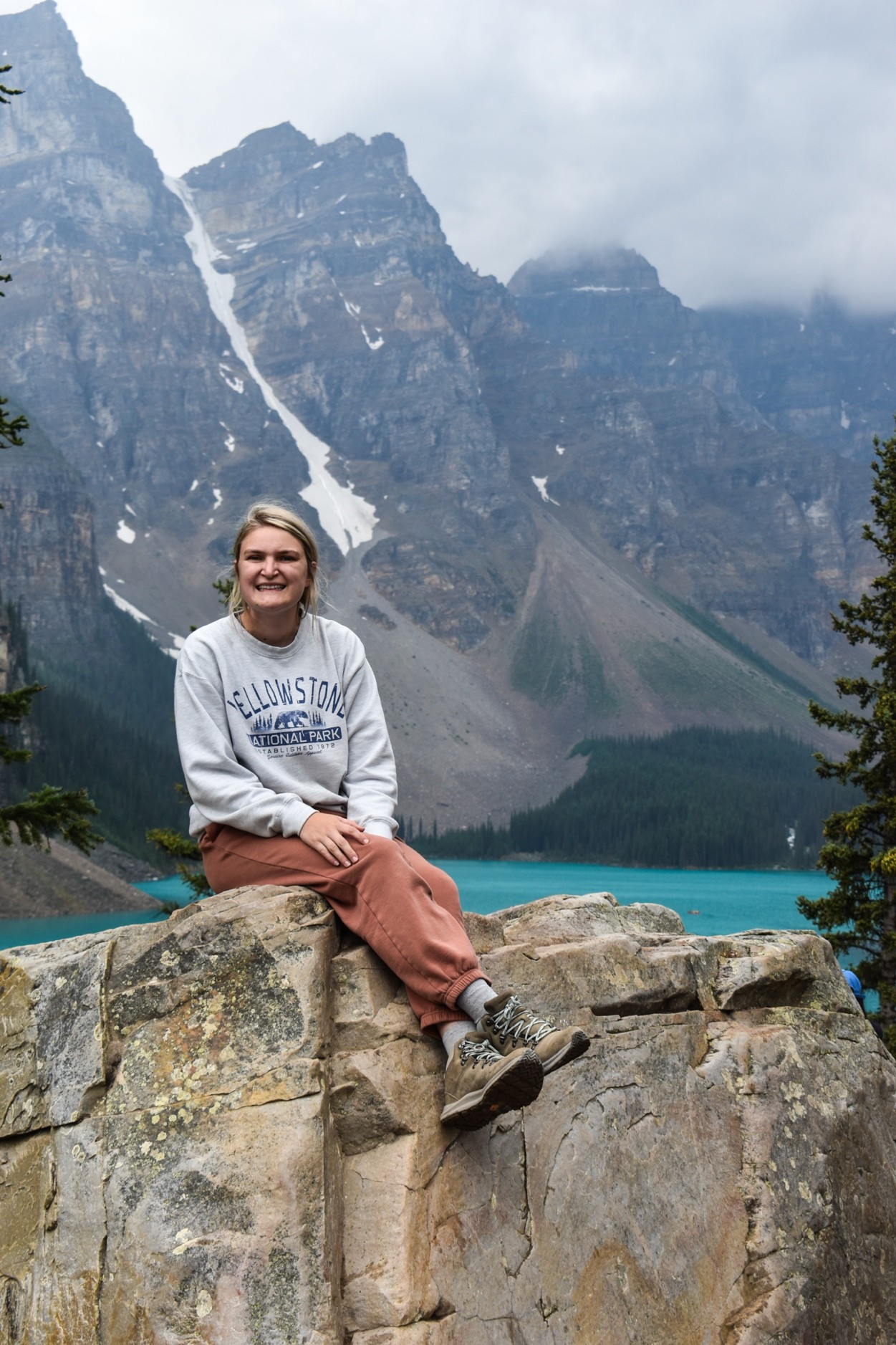 Hannah Christensen posing on a rock with dramatic mountains and lake in the background