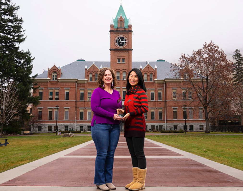 UM faculty members Anisa Goforth (left) and Jingjing Sun hold the 2024 Public Impact Research Award. (Photo by Tommy Martino)