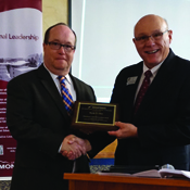 randy cline accepting his award while shaking the hand of another person