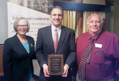 people posing with jacob francom as he accepts his award