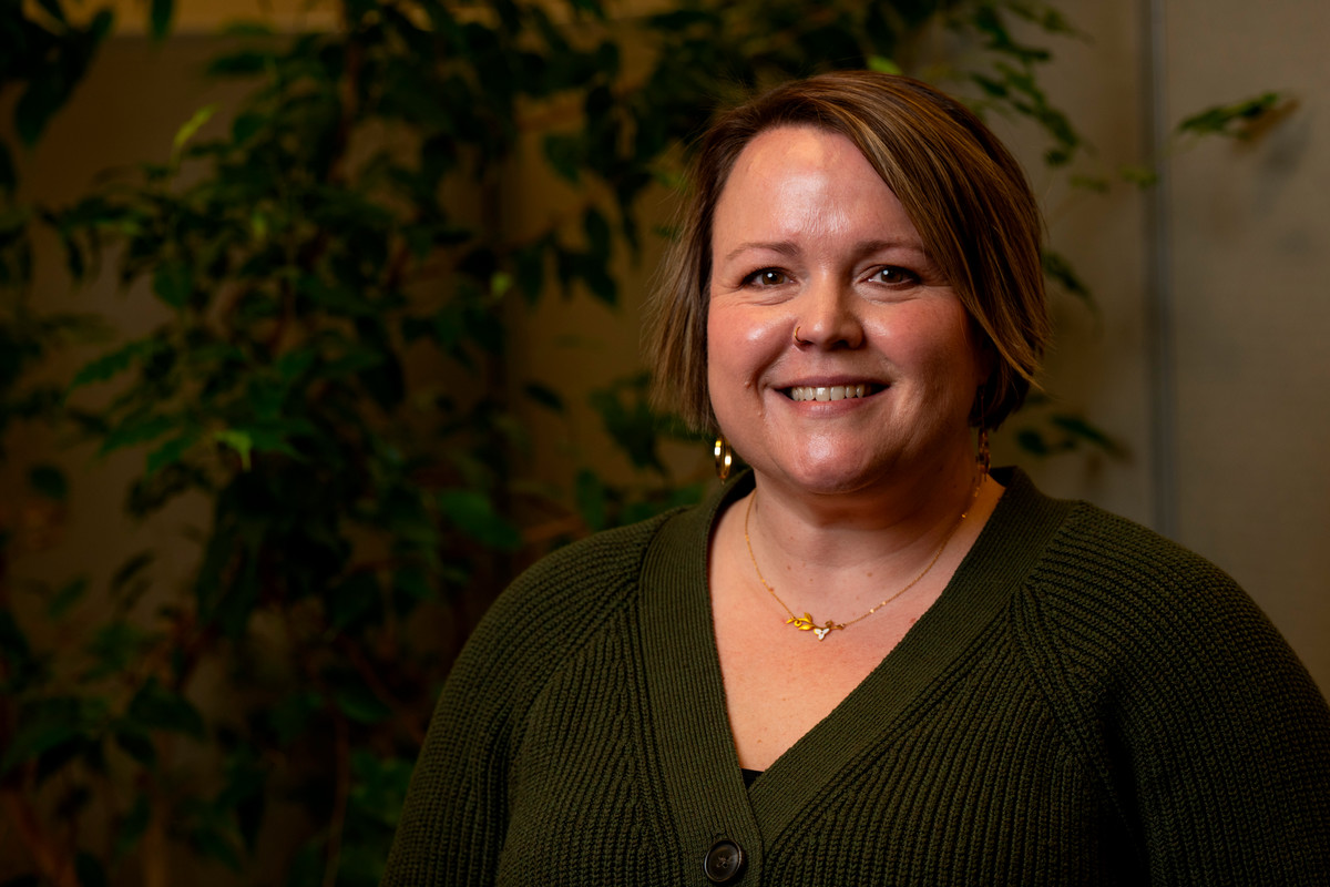 Aimee Elliott next to an office plant.