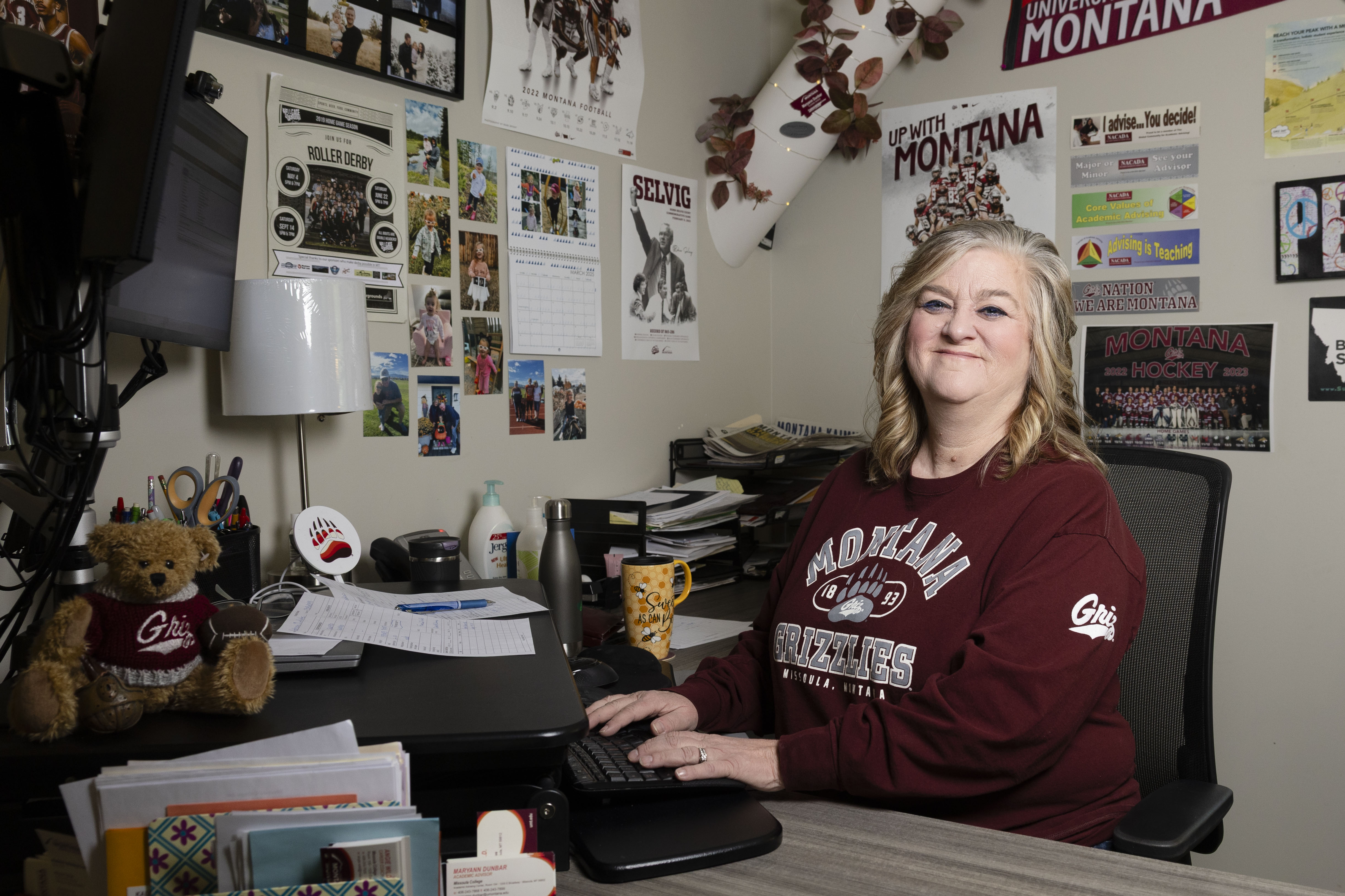Maryann Dunbar at her desk in her office decorated with Griz gear.