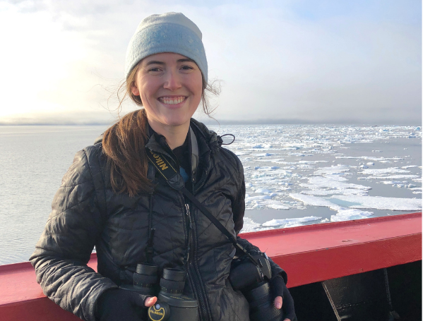 jessica lindsay posing on the deck of a boat with field of broken ice floating on the water behind them
