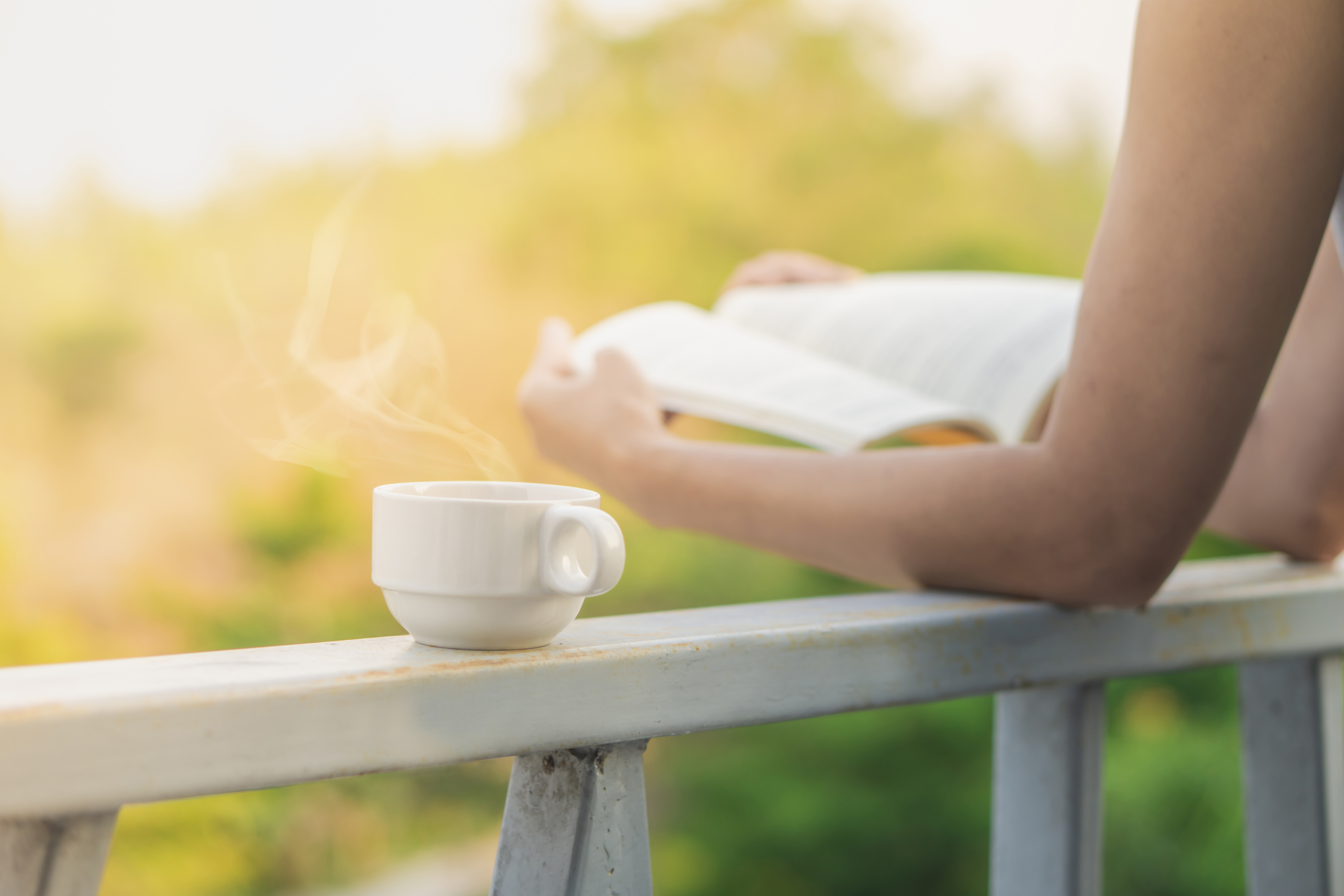 cup hot coffee with woman reading book outdoor