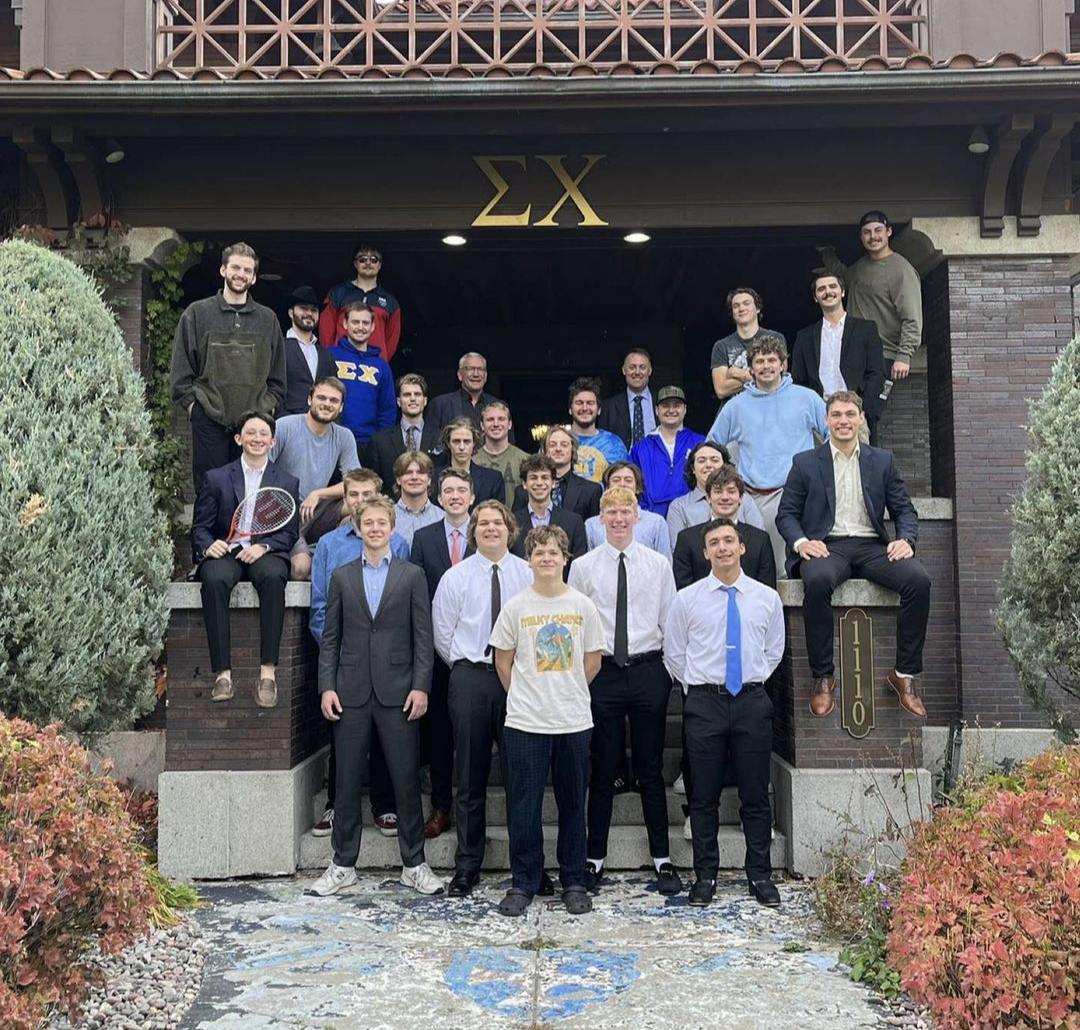members of sigma chi posing on the steps of their fraternity house