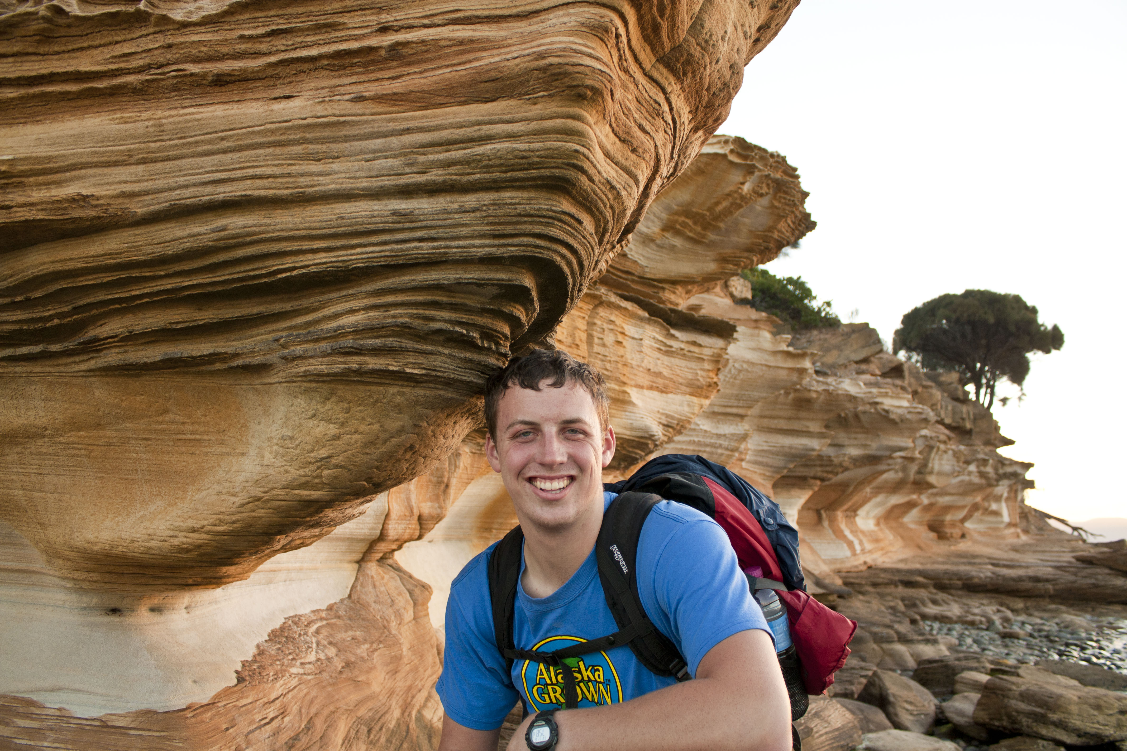 A gentleman standing in front of a beautiful rock