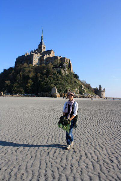 A girl standing on a beach with a castle in the background