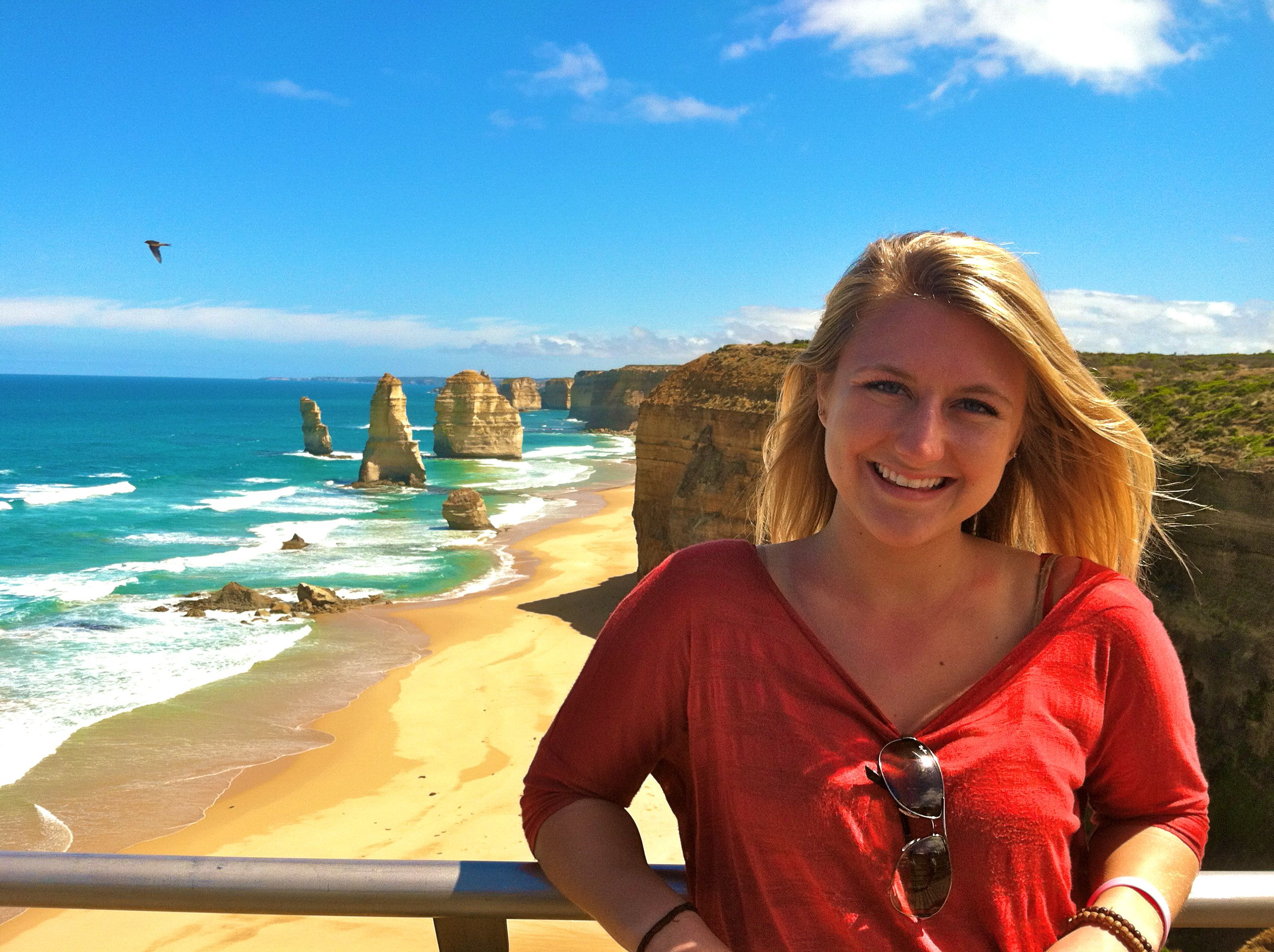 A girl beaming with a beautiful and vibrant beach scene behind her