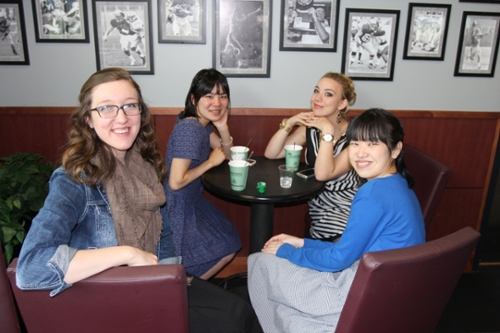 group of four people sitting in a restaurant booth smiling towards the camera