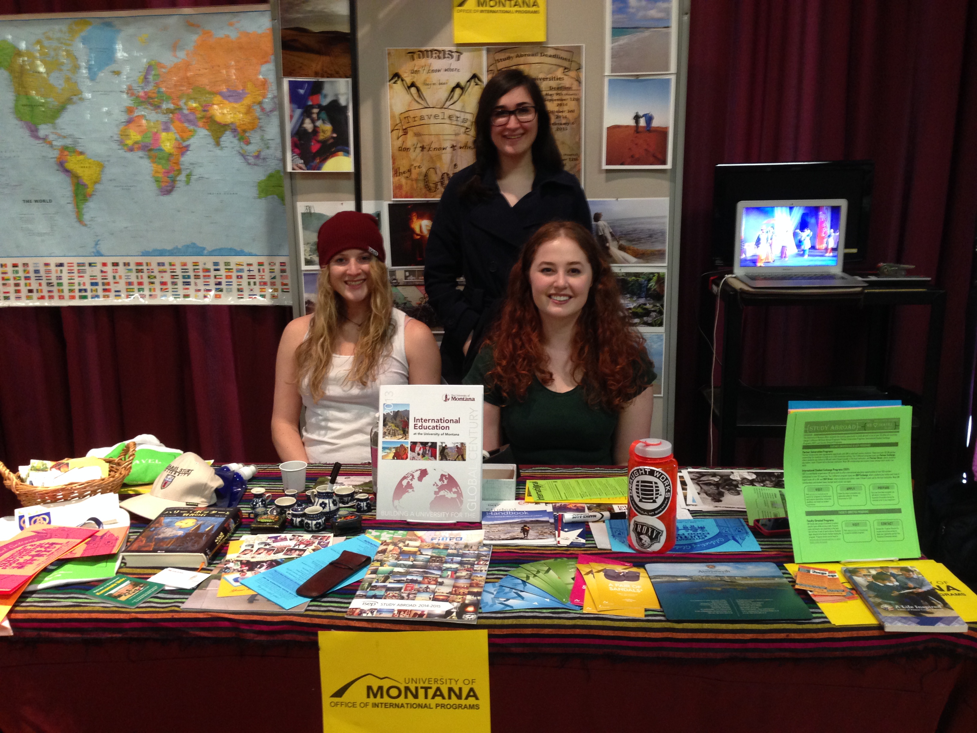 three people at a booth covered in merchandise
