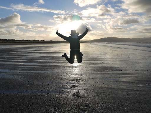 A student jumping on a beach